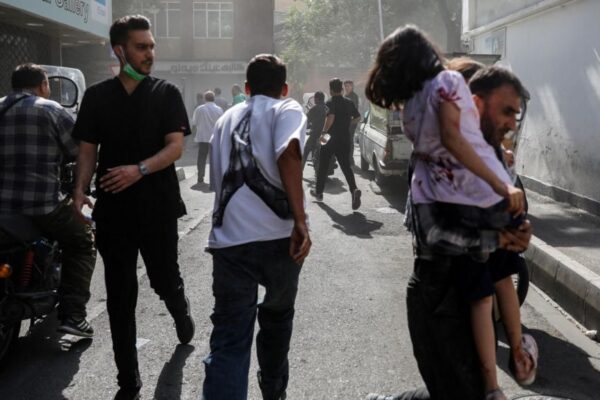 People run along a street amid smoke following the Israeli strikes on Iran, in Tehran, Iran, June 15