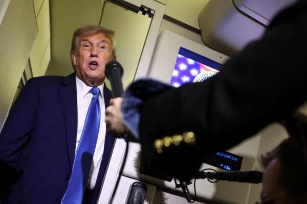 US President Donald Trump is asked questions by reporters on board Air Force One