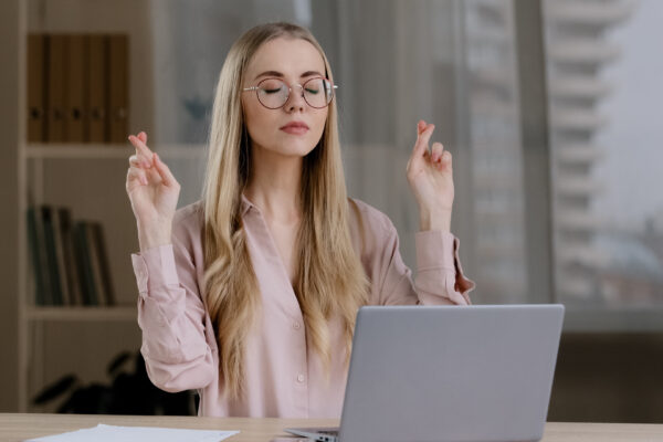 girl using laptop hoping for good luck with her fingers crossed