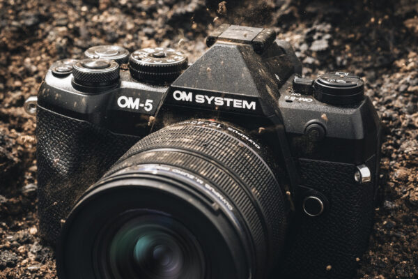 OM System OM-5 II camera caked in mud